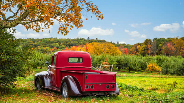 Bowdoin, Maine - October 12, 2018: Old antique red farm truck in apple orchard against autumn landscape background. Blue sky on a sunny fall day in New England.